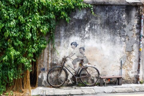 Street art mural boy and girl on bicycle bike on a wall in George Town on Penang